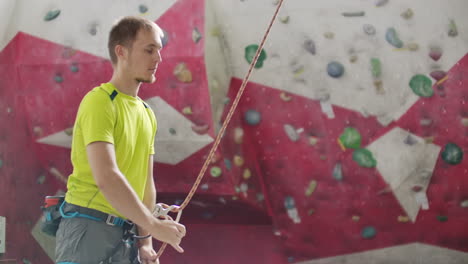 close-up of climber man belaying another climber against a wall with hooks in slow motion