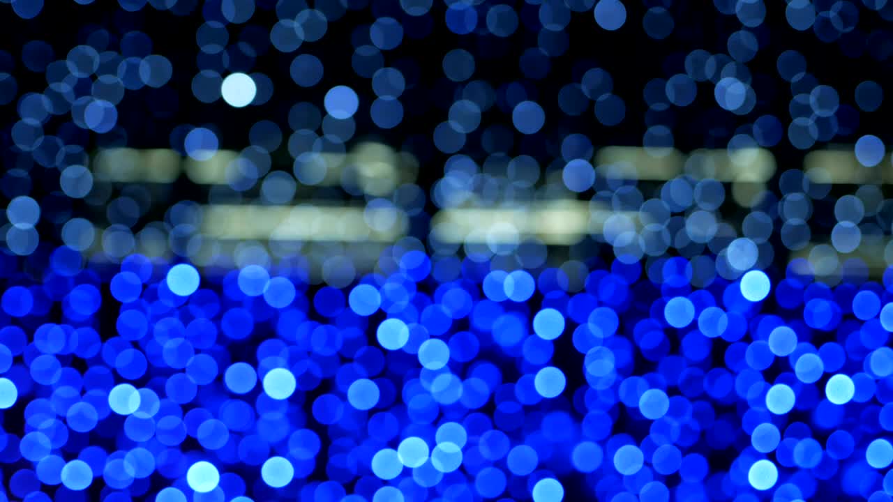 밤의 추상적인 파란색 배경은 멋진 보케로 분해되어 있습니다. 흐릿한 크리스마스 조명 보케.