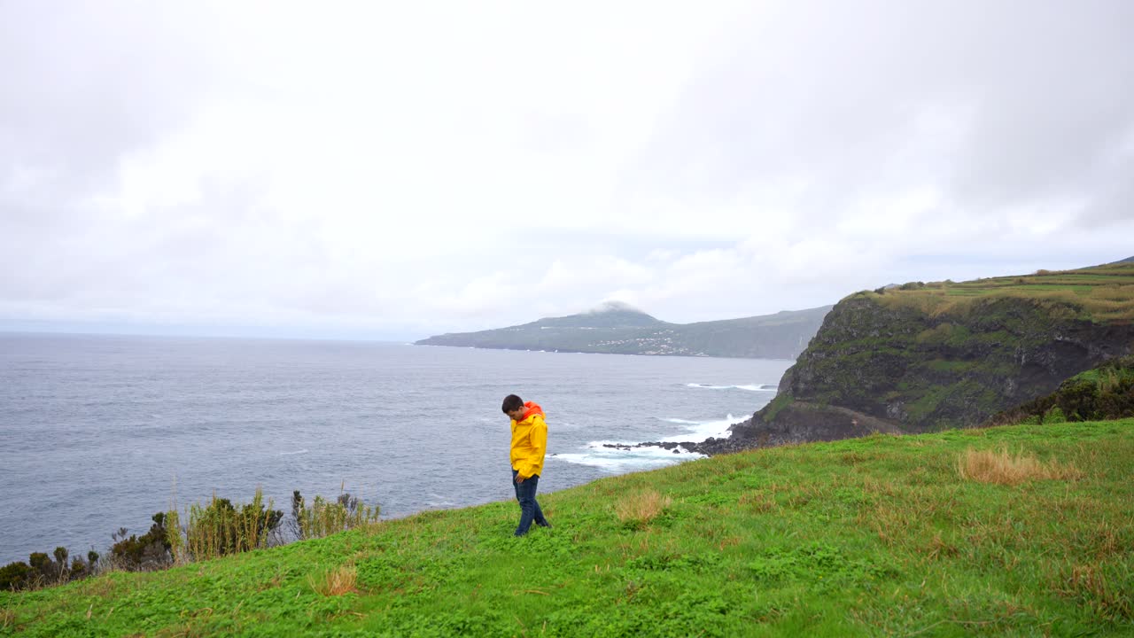 걱정스러운 남자가 그의 문제에 대해 생각하며 해안 절벽의 바닥을 바라보고 있습니다.