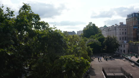 Landing-footage-on-flat-roof-of-Temple-Station-building.-River-Thames-and-bridges-across-gradually-hiding-behind-row-of-trees-on-waterfront.-London,-UK