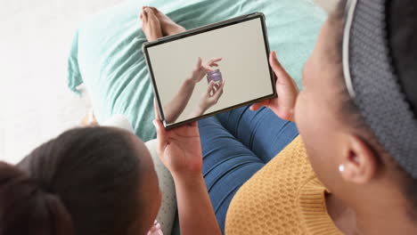 African-american-mother-and-daughter-using-tablet,-online-shopping-for-beauty-products,-slow-motion