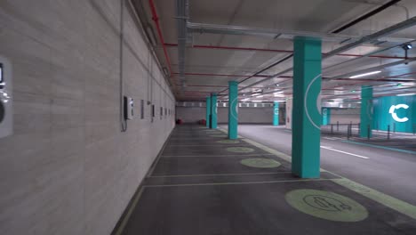 panorámica de izquierda a derecha: puntos de carga de vehículos eléctricos vacíos en un estacionamiento subterráneo