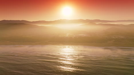 sun reflecting in the sea water near the shore. silhouettes of mountains and some features of city hardly seen in the rays of sunset.