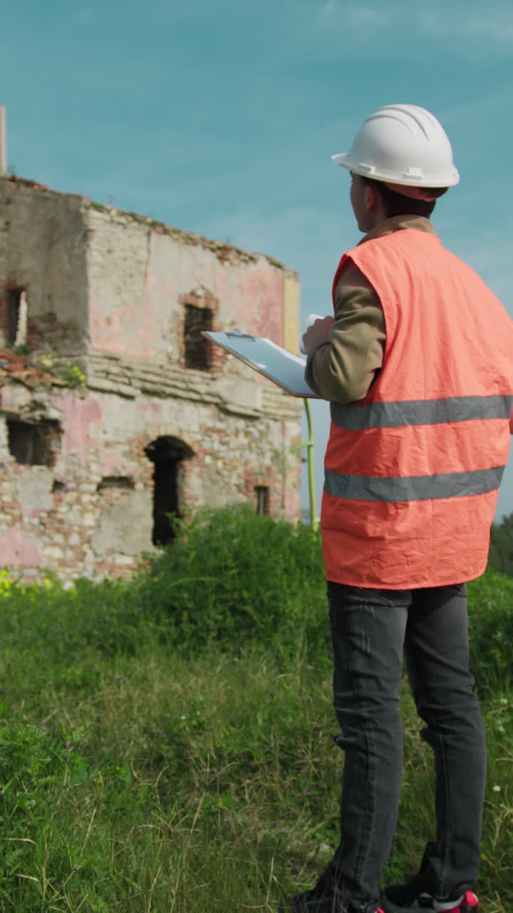 Engineer On The Construction Site Looking At The Old Building And Taking Notes