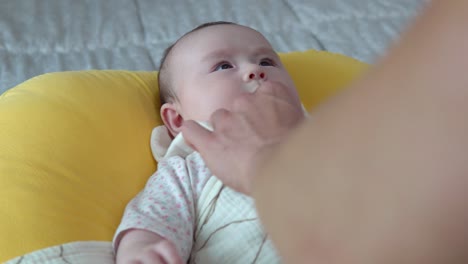 침대에 누워 있는 귀여운 아기를 돌보는 부모의 손 - 클로즈업
