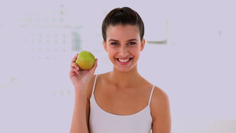 mujer hermosa divertida oliendo y mostrando una manzana