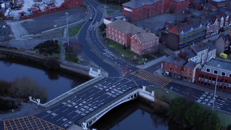 Aerial-early-morning-city-street-traffic-commuting-intersection-lanes-crossing-curved-river-orbit-left-looking-downwards