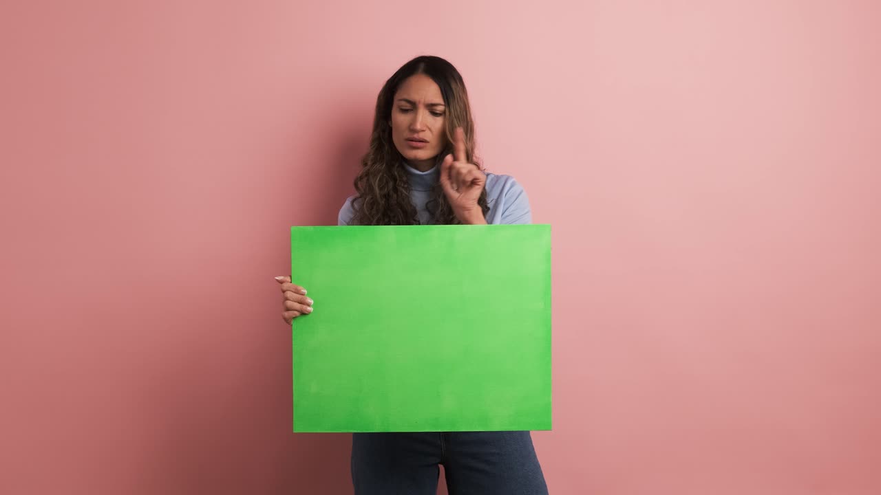 Colombian woman holding a blank green panel and gesturing negatively