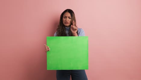 colombian woman holding a blank green panel and gesturing negatively