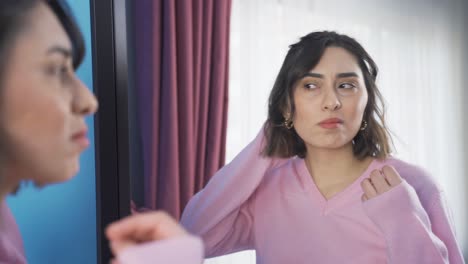 Unhappy-young-woman-looking-at-her-hair-in-the-mirror.