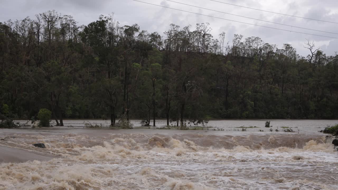 Coomera, Gold Coast, 2 January 2024 - Trees and turbulent water across the Coomera River Causeway under flood waters from the 2024 Storms in January