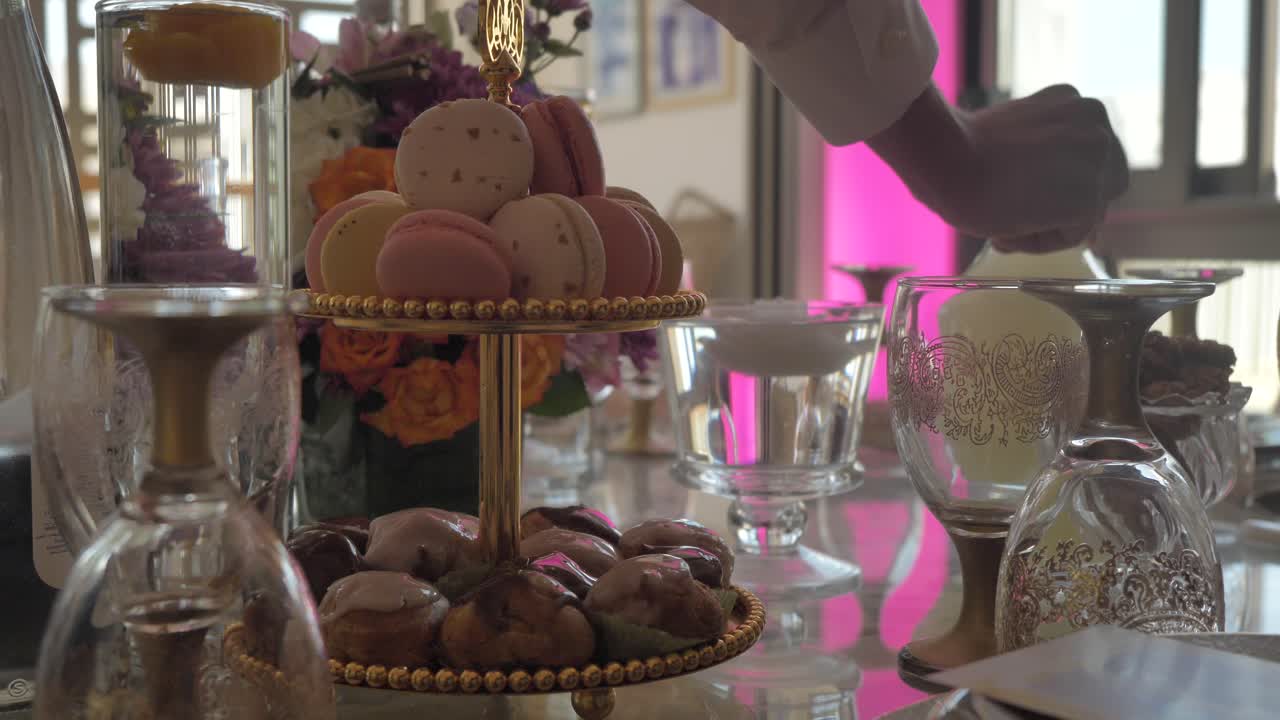 hombre colocando una jarra en la mesa de la boda - macarons y choux glaseado en un puesto de pasteles