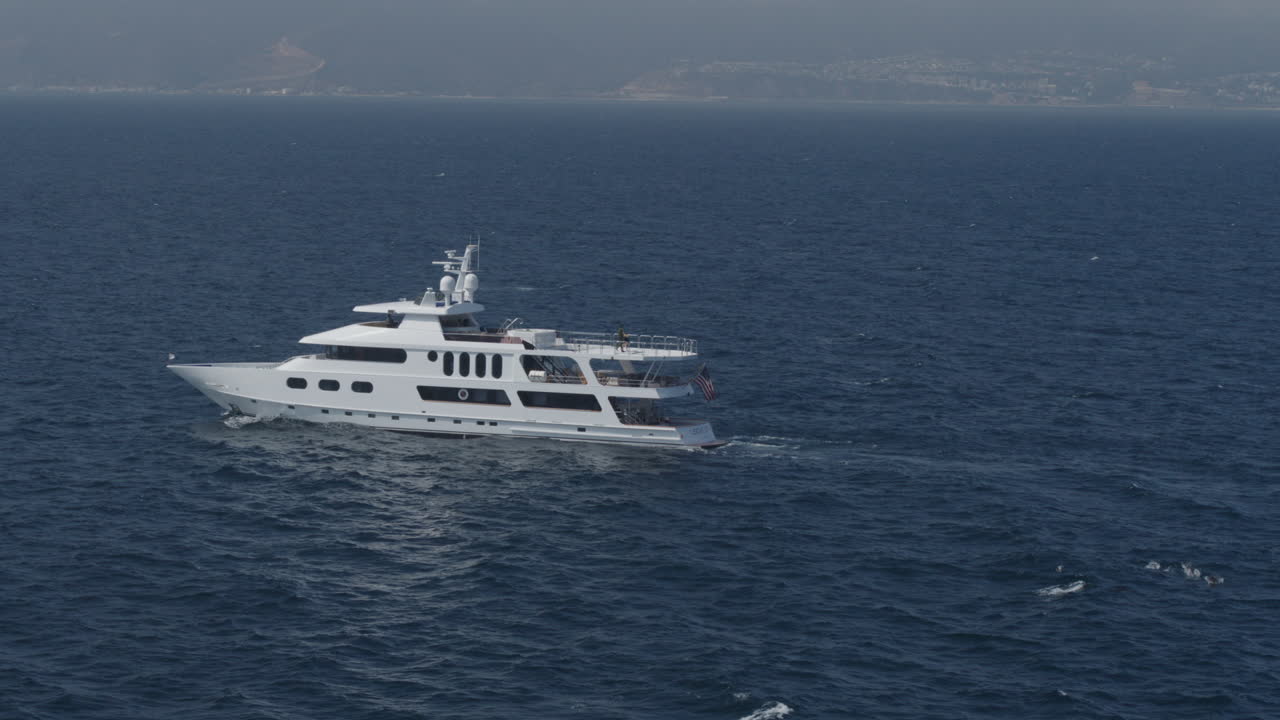 Ripresa aerea con drone in allontanamento di uno yacht che naviga nel blu profondo del mare