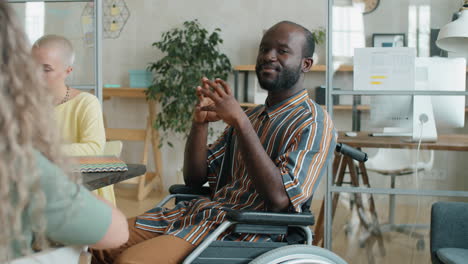 positive african american businessman in wheelchair posing for camera in office