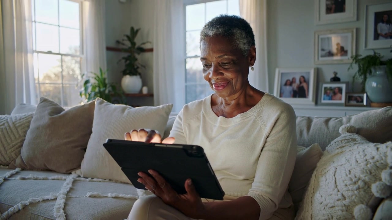 Senior Woman Using a Digital Tablet on a Sofa at Home