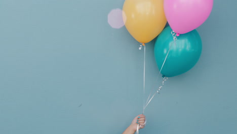 hand holding colorful ballons floating happy birthday party celebration concept on wall copy space intro 4k