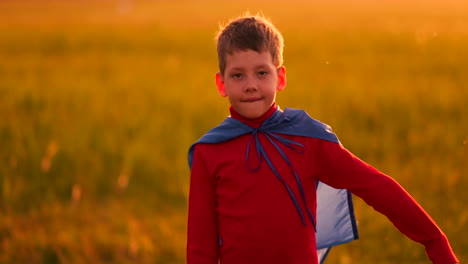 Un-Niño-Vestido-Como-Un-Superhéroe-Parado-Con-Una-Máscara-Y-Una-Capa-Roja-Corre-Riendo-Al-Atardecer-En-El-Campo-De-Verano.-Noche-De-Verano-El-Niño-Sueña-Y-Hazañas-Heroicas-Y-Cómics