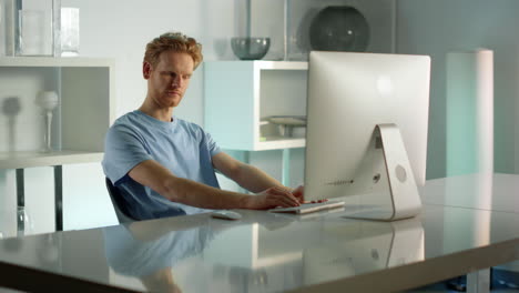 creative writer working computer at home office. focused ginger man write email.