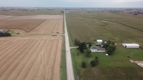 Vista-Aérea-De-La-Conducción-De-Camiones-En-Un-Camino-De-Ripio-En-La-Zona-Rural-De-Iowa