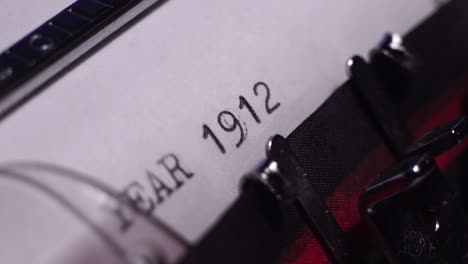 year 1912, typing on white paper in vintage typewriter, macro close up