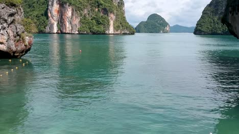 imágenes de drones de un bote de cola larga navegando alrededor de las islas de tailandia con las formaciones rocosas de piedra caliza que sobresalen del agua y el océano en el fondo-3