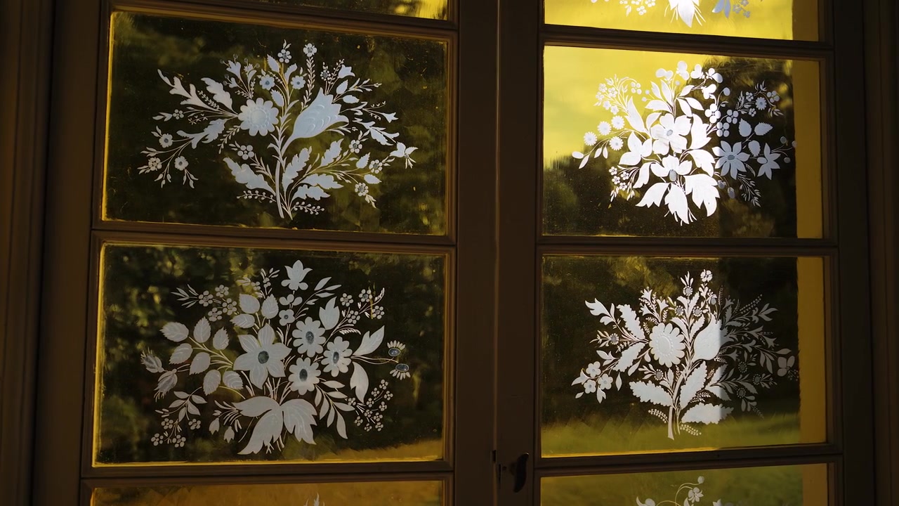 Nærbilde av elegante gule frostede glassvinduer med intrikate hvite etsede blomstermønstre