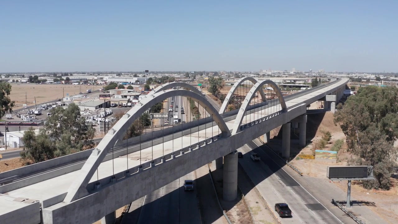 Carrellata aerea ravvicinata della campata del ponte a doppio arco sulla ferrovia ad alta velocità della California sopra il Viadotto Cedar a Fresno, California. 4K