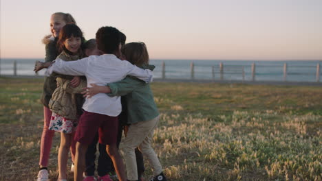 portrait of happy group of children group hug enjoying fun games on seaside beach park at sunset