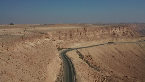 Mitzpe-Ramon-Mitzperamon-Israel-Negev-desert-highway-drone-dolly-in-flying-car-road-mountains-sand-middle-east-middleast-jordan-palestine-crater-Ramon-buildings-stones-stone