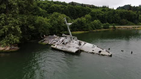 aerial orbit around uss plainview shipwreck in columbia river coastline on cloudy day