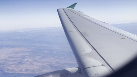 ala de un avión vista desde un asiento de pasajeros con el paisaje marroquí en el fondo
