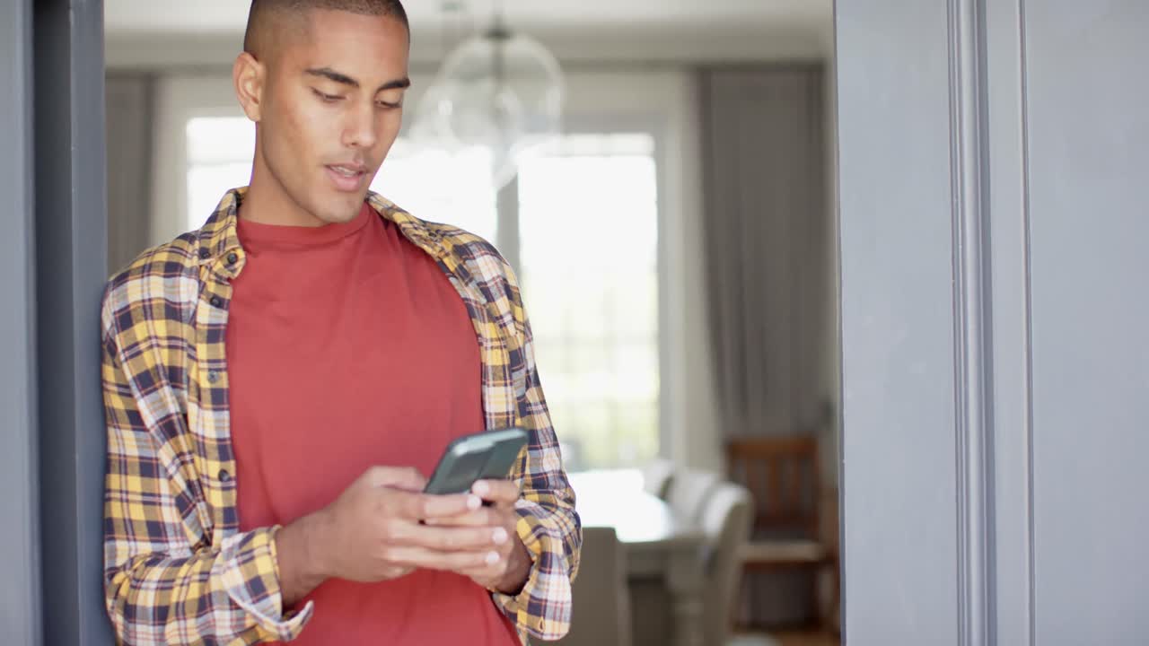 Happy biracial man using smartphone at home, slow motion