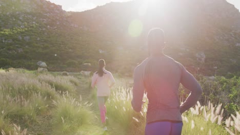 diverse fit couple exercising running across a field in the countryside