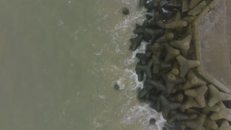 Aerial-establishing-view-of-Port-of-Liepaja-concrete-pier,-Baltic-sea-coastline-,-foggy-day-with-dense-mist,-moody-feeling,-big-storm-waves-splashing,-ascending-birdseye-drone-shot