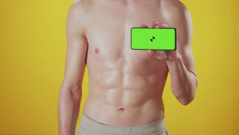 men's hands show phone with green screen against background of pumped up press, closeup on yellow background. studio shooting, mockup, chromakey