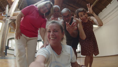 Happy-woman-taking-selfie-with-friends-after-workout-in-ballroom