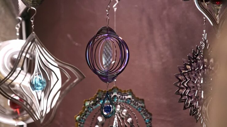 Diversi caleidoscopi a spirale appesi ruotano riflettendo luce e colore.