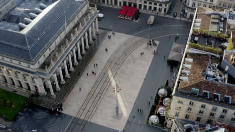 opera house grand theater square with people, vehicles and trolley tram tracks, aerial orbit reveal shot