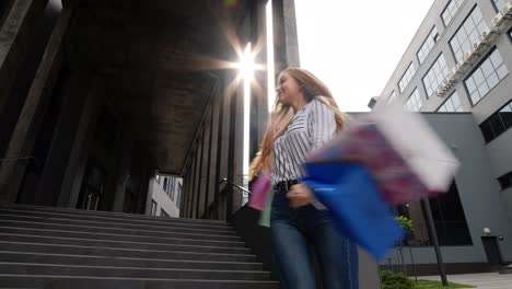 girl walking and showing black friday inscription on shopping bags, rejoicing discounts in store