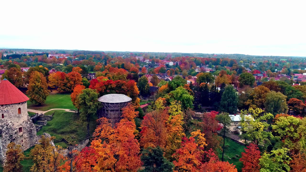 castillo de cesis e iglesia luterana rodeada de hermosos árboles otoñales en letonia