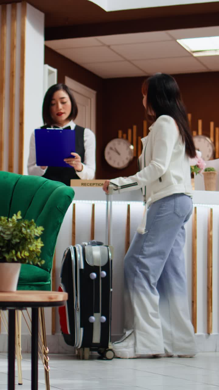 Video verticale: ospite di un hotel che legge e firma i moduli di registrazione nella hall