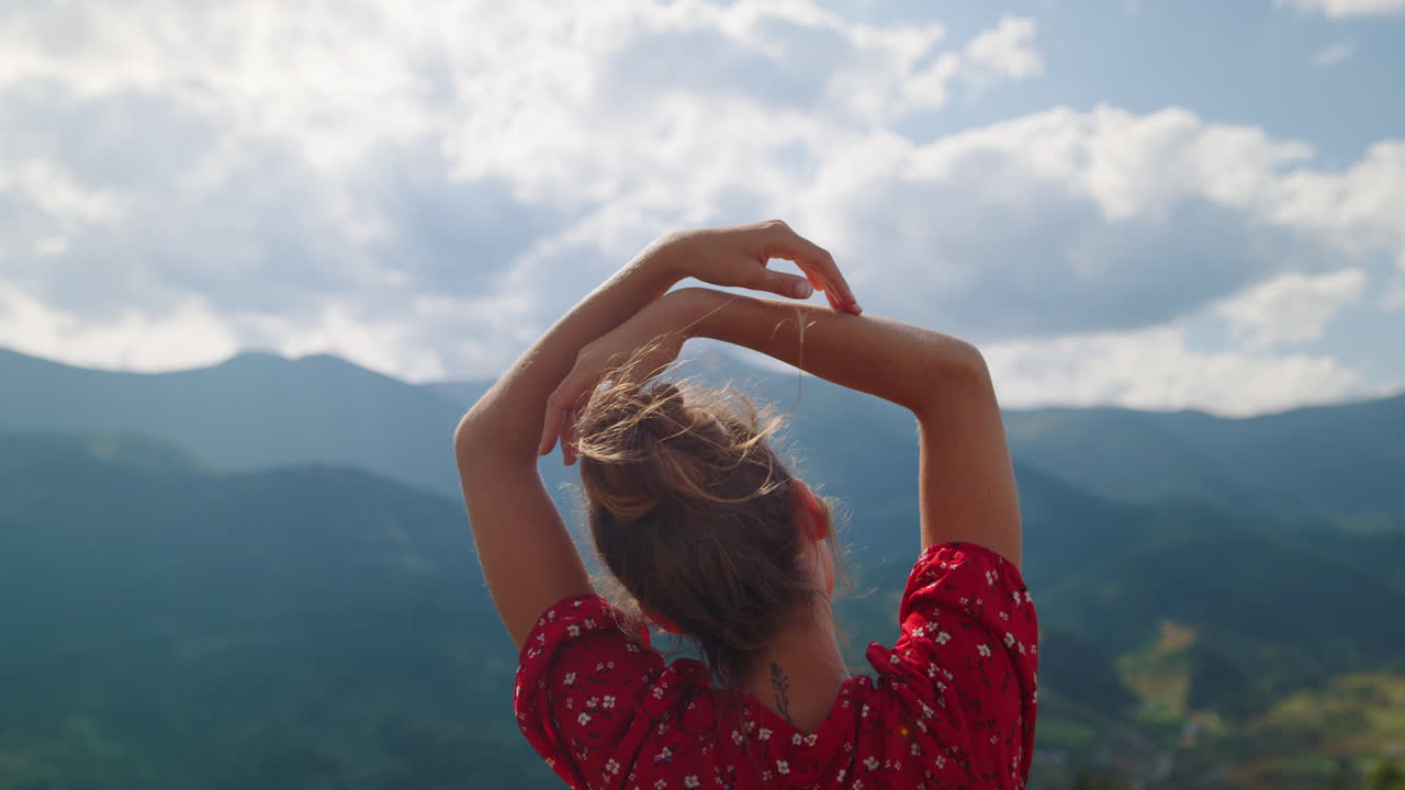 산에서 손을 들어 올리고 서 있는 소녀. 자연에 대한 여성의 뒷모습.