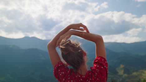 girl standing raising hands in mountains close up. back view woman on nature.