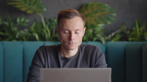 the man looks at his laptop and thinks. decision-making in education and business. thinking and inventing while sitting with a laptop