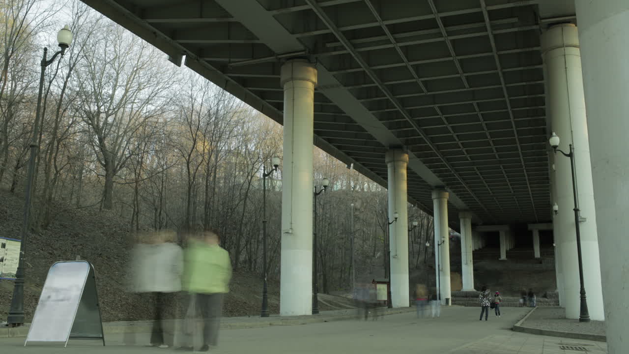 People in blur walking under the bridge