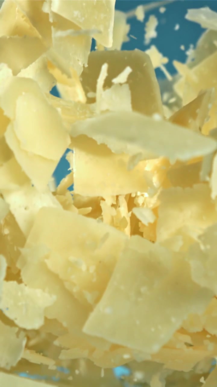 Copeaux de fromage Parmesan tombant au ralenti sur fond bleu