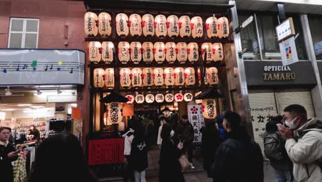 people walking past illuminated lanterns and shops