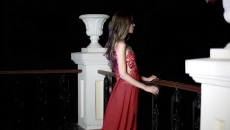 woman in red evening gown on balcony at night