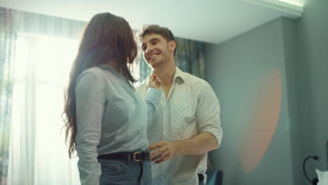 una pareja sonriente abrazándose en una habitación de hotel. una chica y un chico sorprendidos de pie en una habitación acogedora.