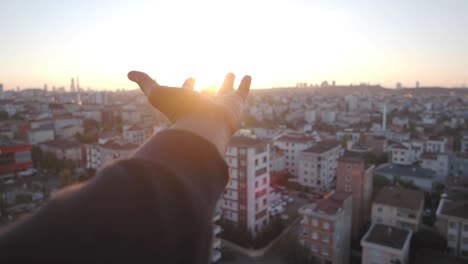 mano alcanzando hacia el amanecer sobre la ciudad